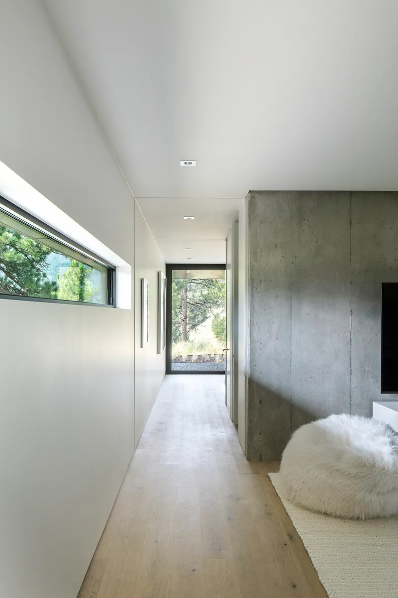 Corridor with board-formed concrete wall and high clerestory glazing leading to an exterior door