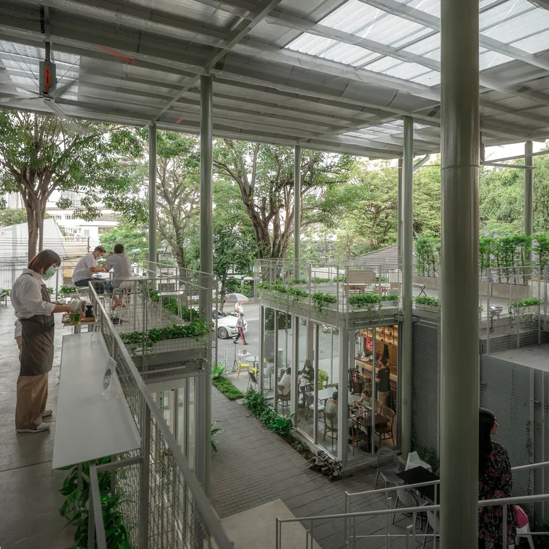 Upper-level walkway overlooking the multi-story atrium with mesh balustrades and trees growing through the space