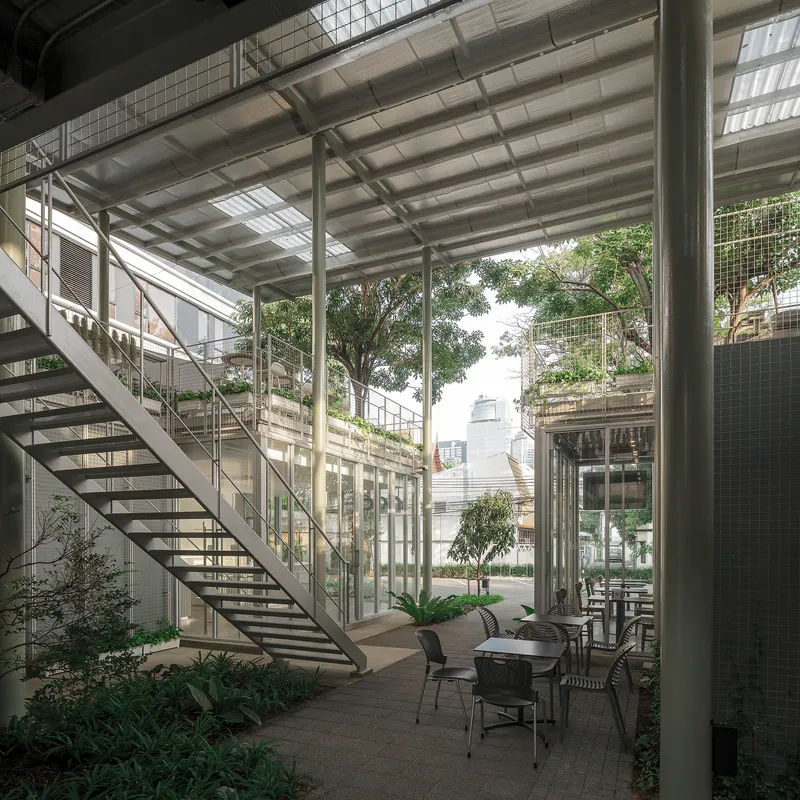 View across the courtyard showing the open-tread staircase, steel columns and planted ground-level terrace