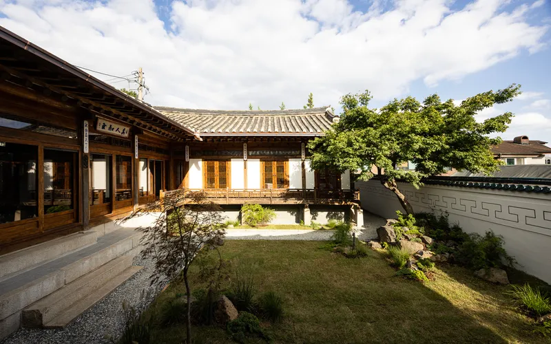 Courtyard view of timber pavilions with tiled roofs surrounding a gravel and lawn garden