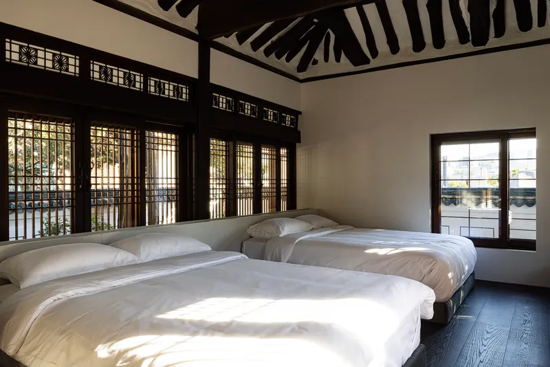 Sleeping room with latticed windows filtering morning light onto low platform beds