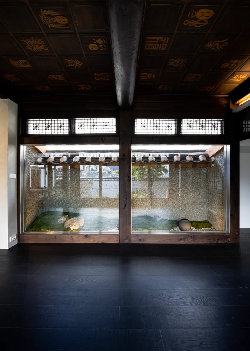 Interior view through latticed windows to a gravel courtyard with traditional tiled roof overhang