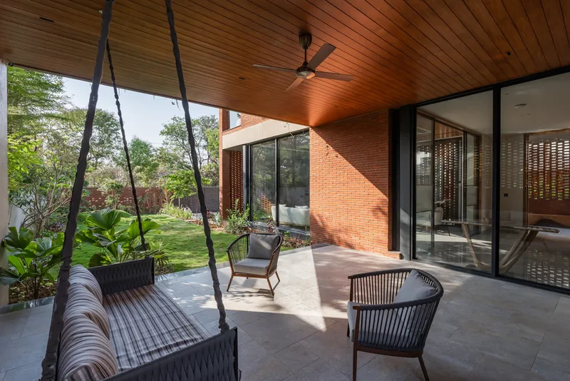 Shaded terrace with suspended rope swing and timber ceiling overlooking a landscaped garden