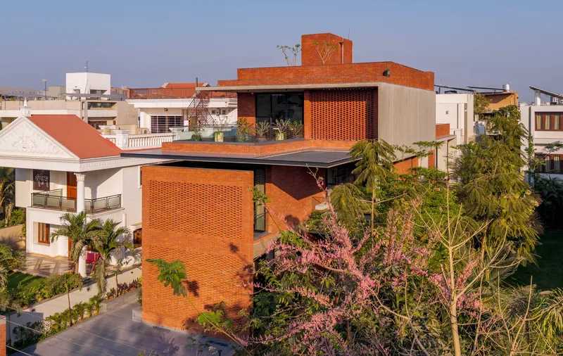 Stacked brick volumes with patterned screens and cantilevered roof plane surrounded by flowering trees