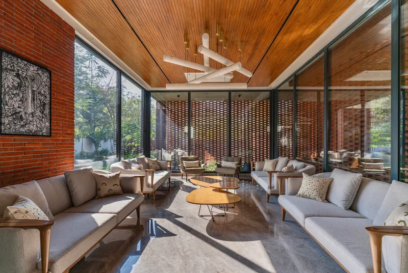 Living room with timber slat ceiling and floor-to-ceiling glazing overlooking perforated brick screen
