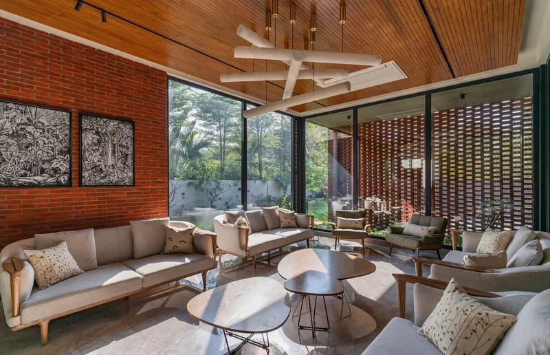 Living room with timber slatted ceiling and brick walls opening to courtyard garden through glazing