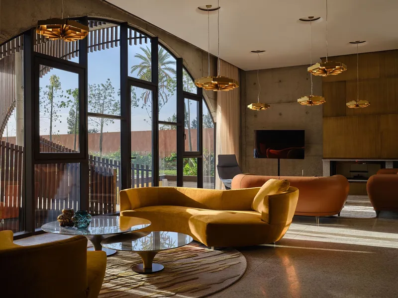 Living space with brass pendant lights and arched glazing framing palms beyond