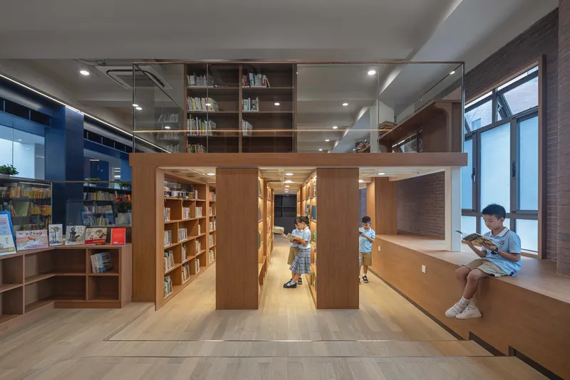 Library space with timber bookshelves and built-in window seating where students read during daytime