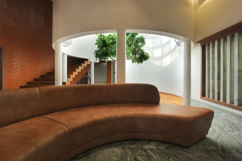Curved leather sofa facing the central courtyard with white columns and brick stair wall beyond