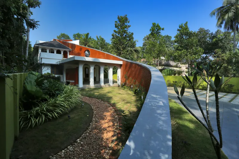 Exterior view of the curved red brick roof wall and white colonnade amid palm trees and lawn