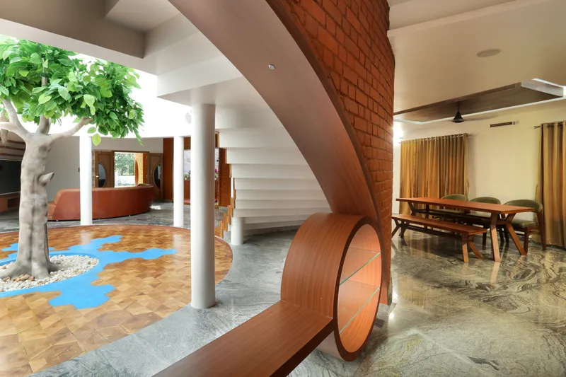 Curved timber staircase wrapping around a white column beside the exposed brick wall and dining area