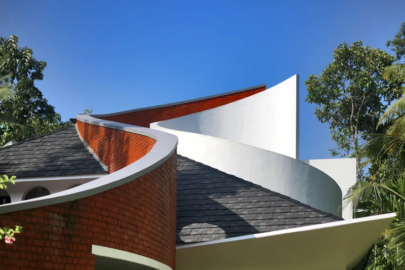 Close-up of the intersecting curved roof shells with terracotta tile and white painted surfaces against foliage