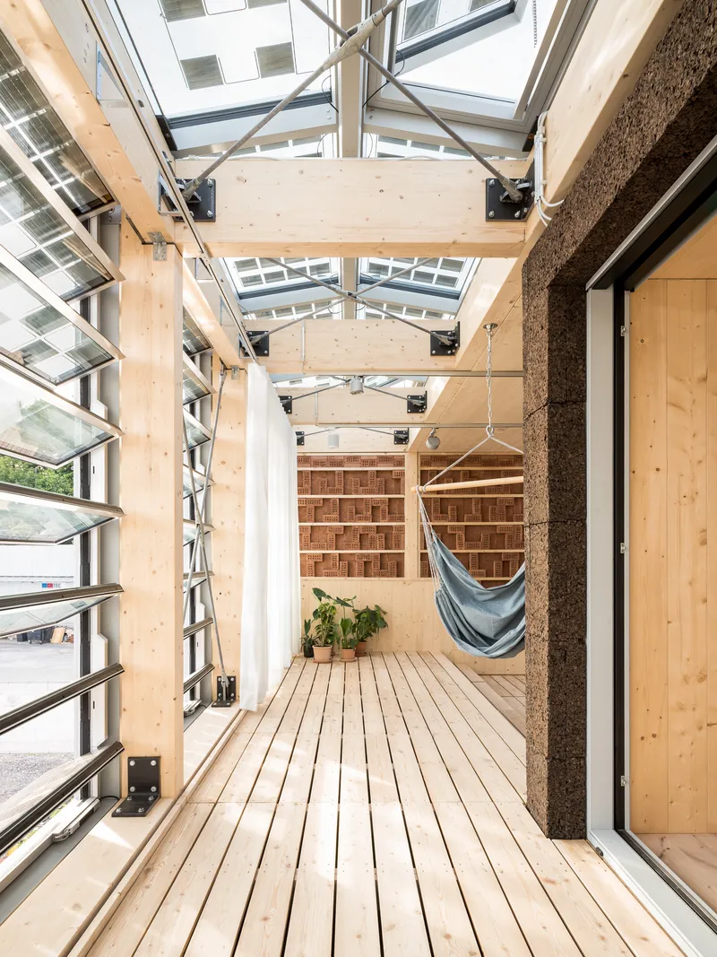 Covered deck with timber flooring, exposed roof beams and hammock beside cork-clad column