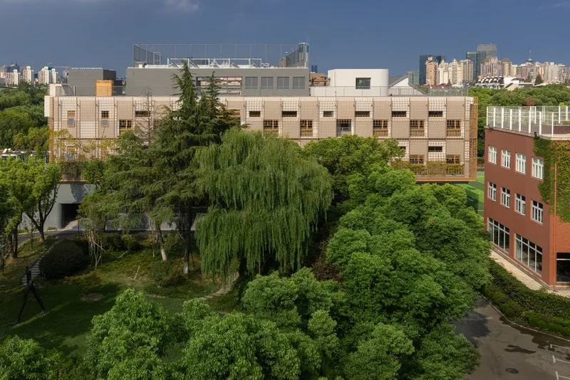 Aerial view of the tiled facade surrounded by mature willow and deciduous trees in the campus landscape
