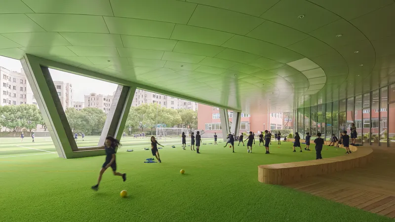 Interior turf field beneath a green ceiling with angled columns and students playing