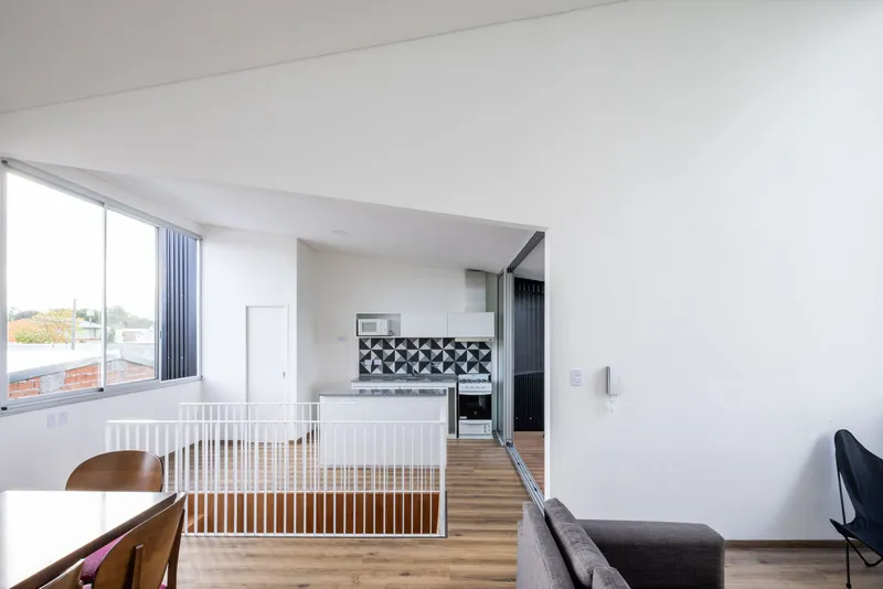 Living space with slatted stair guard separating kitchen area with patterned tile backsplash in morning light