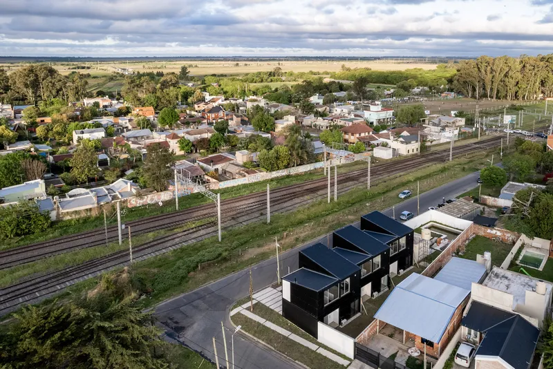 Aerial perspective of the townhouse cluster with black corrugated cladding framed by railway lines and residential streets