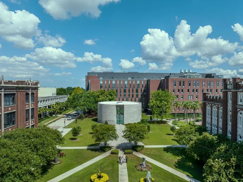 Aerial view of the circular chapel set within a campus quadrangle under summer clouds