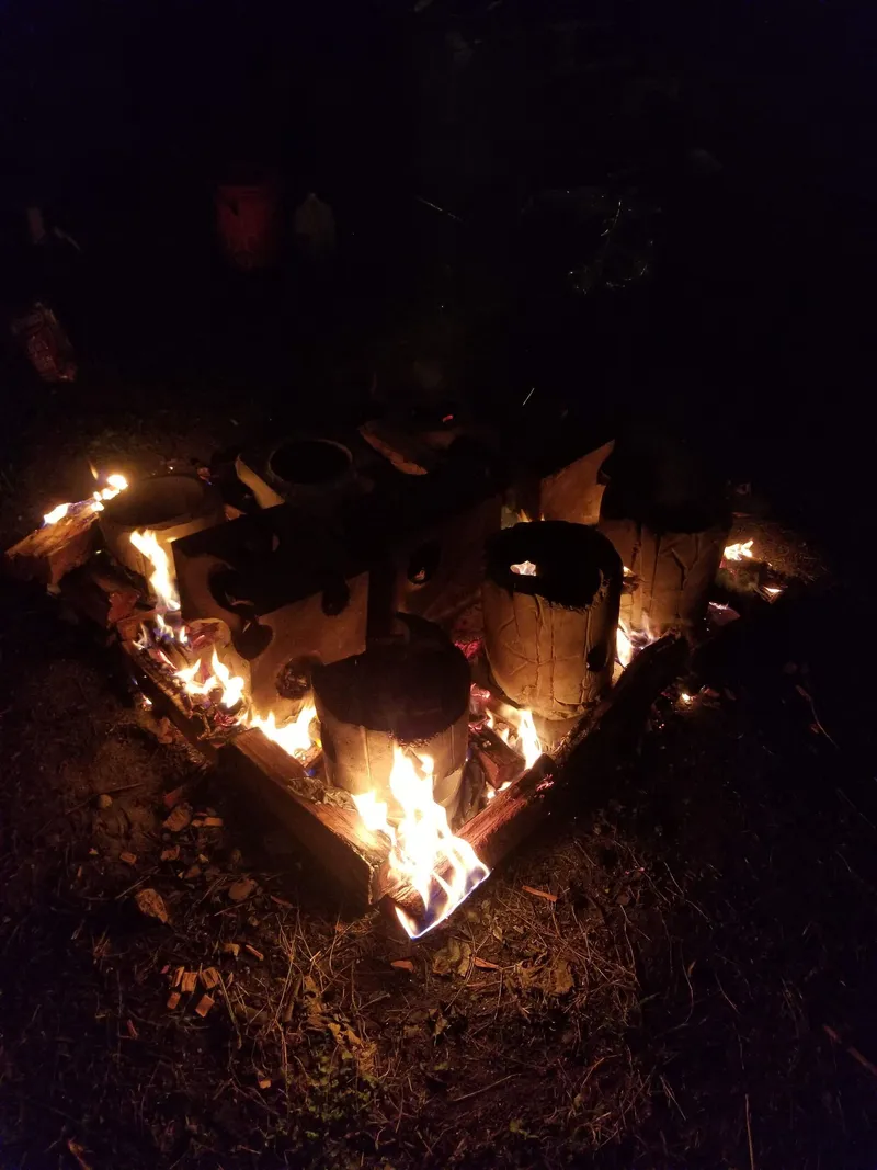 Fired ceramic tile structure with circular voids illuminated by flames at night