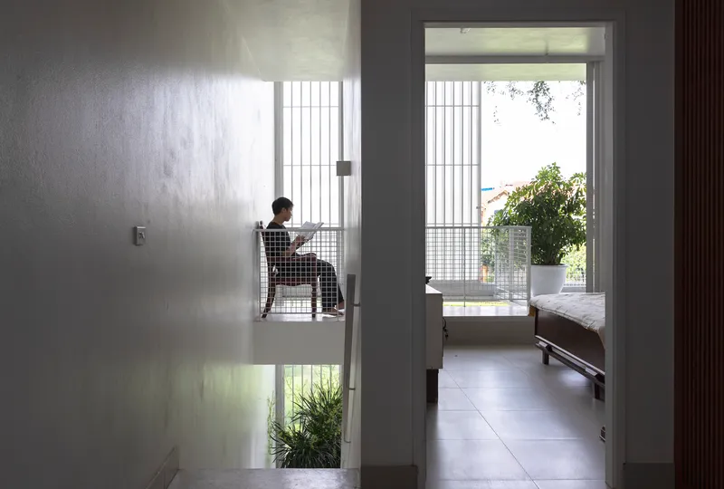 Interior hallway view through doorways to a bedroom with a person seated beside a translucent screen
