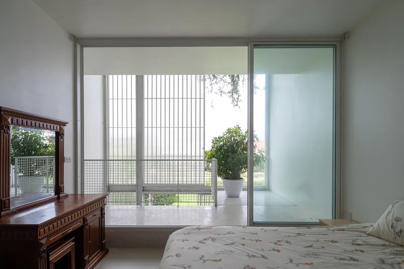 Bedroom with sliding glass doors opening onto a screened balcony overlooking greenery