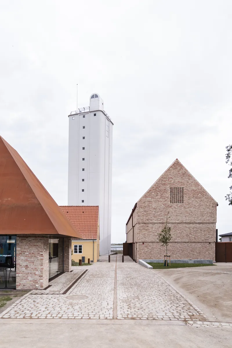 Plaza view showing white tower, brick gabled building, and low structures with terra cotta roofs