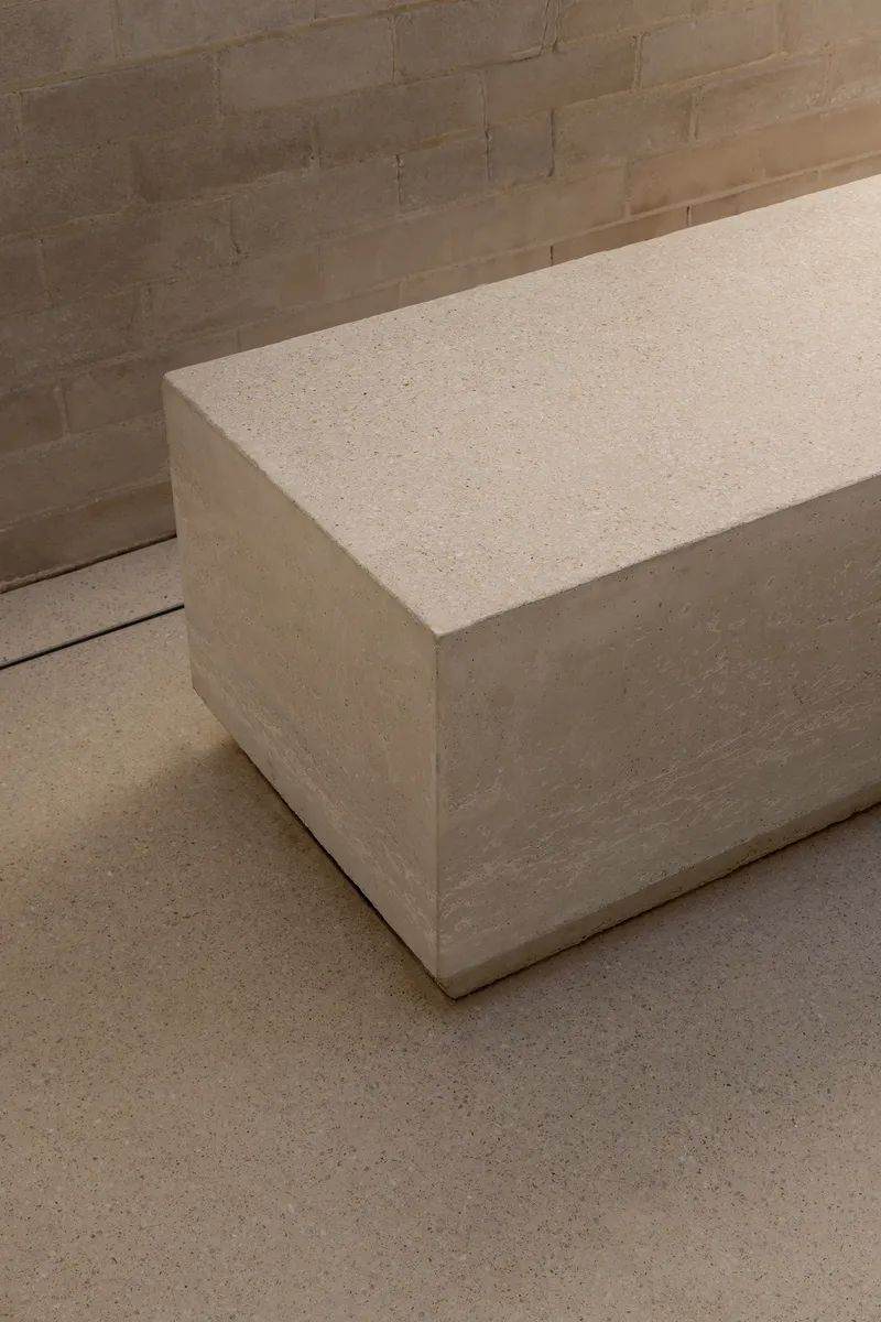 Corner detail of cast stone bench against brick wall with terrazzo floor