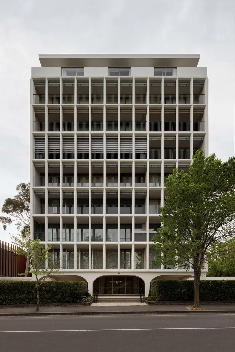 Street facade with repetitive concrete column grid and recessed balconies flanked by street trees