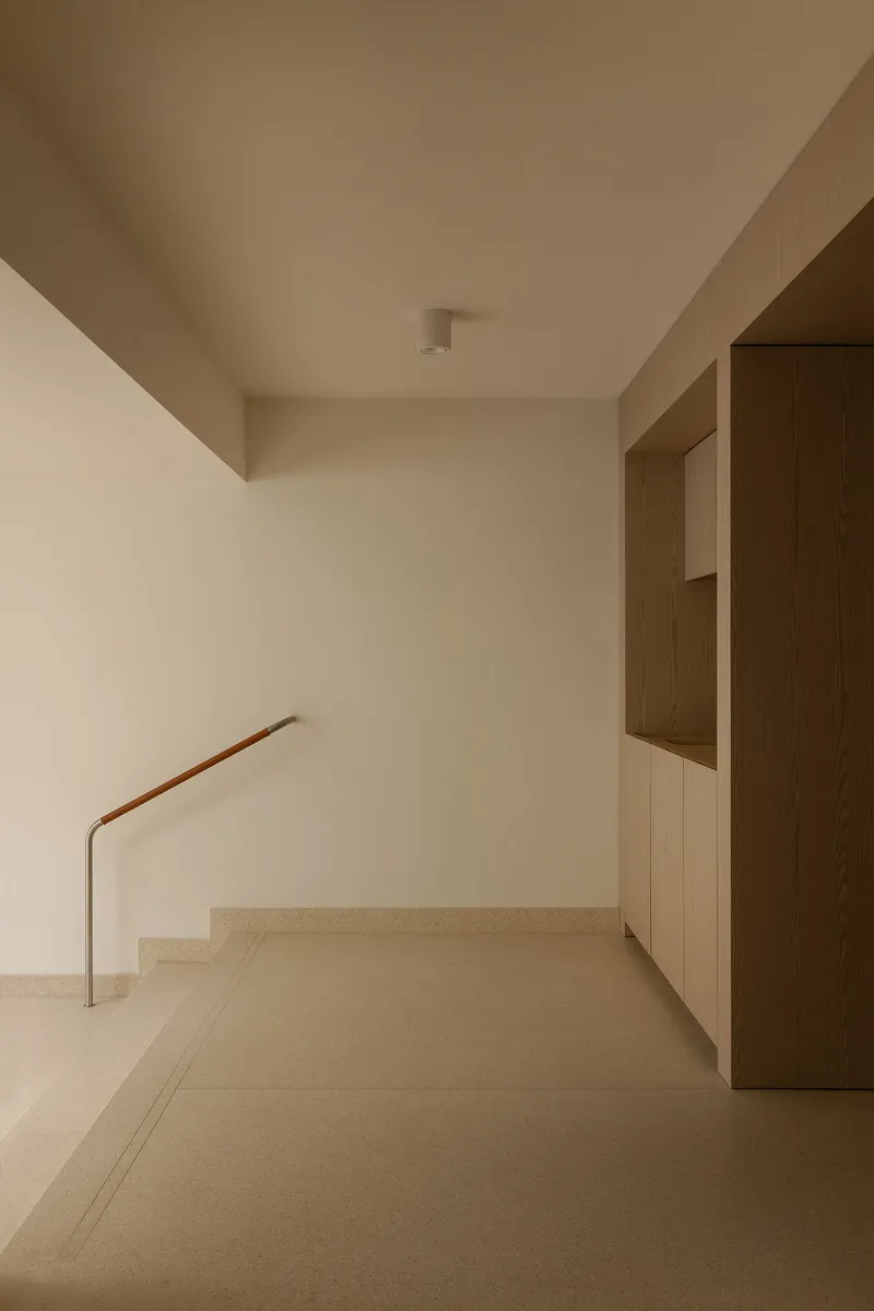 Upper landing with timber wall paneling and a simple metal handrail against pale walls