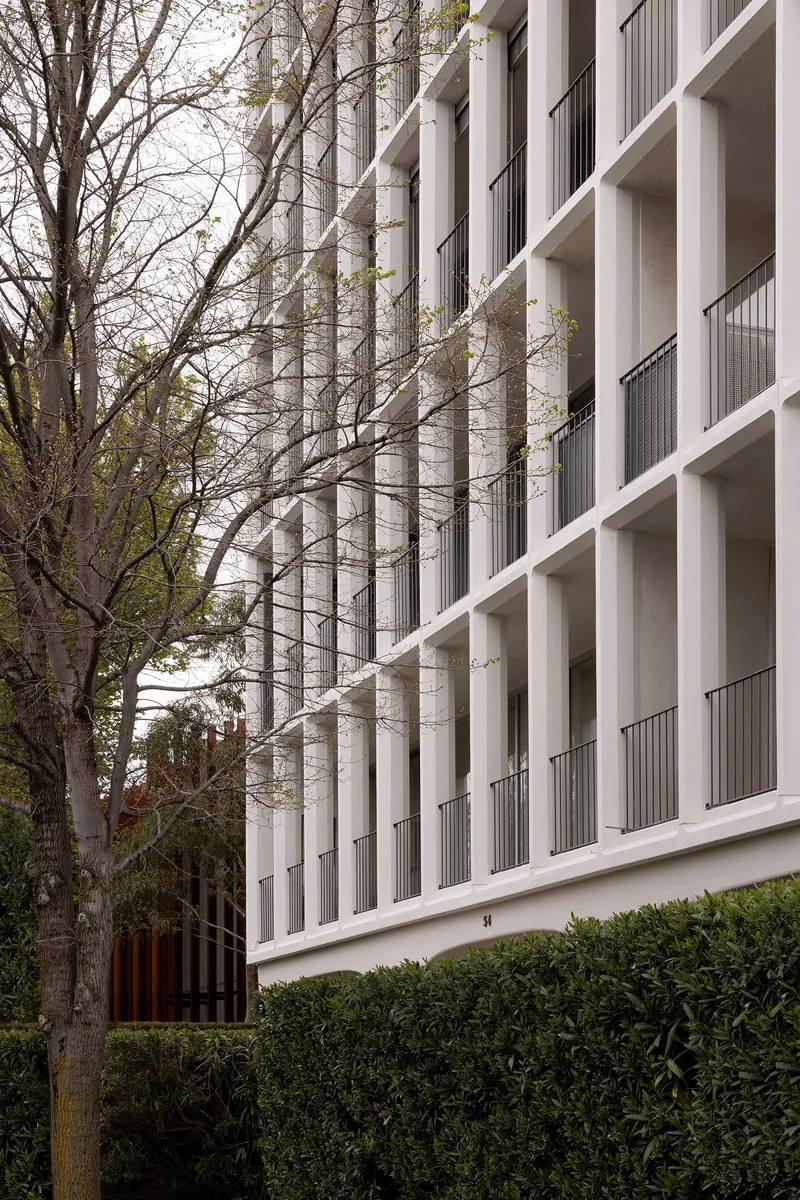 Oblique view of the facade showing concrete columns and balconies with bare tree branches