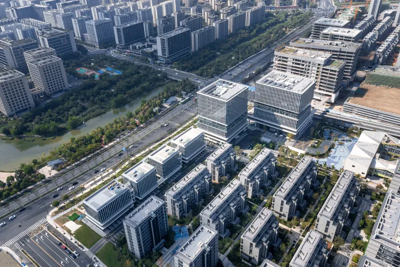 Aerial view of mixed-use development with striped facade towers and low-rise residential blocks beside a river