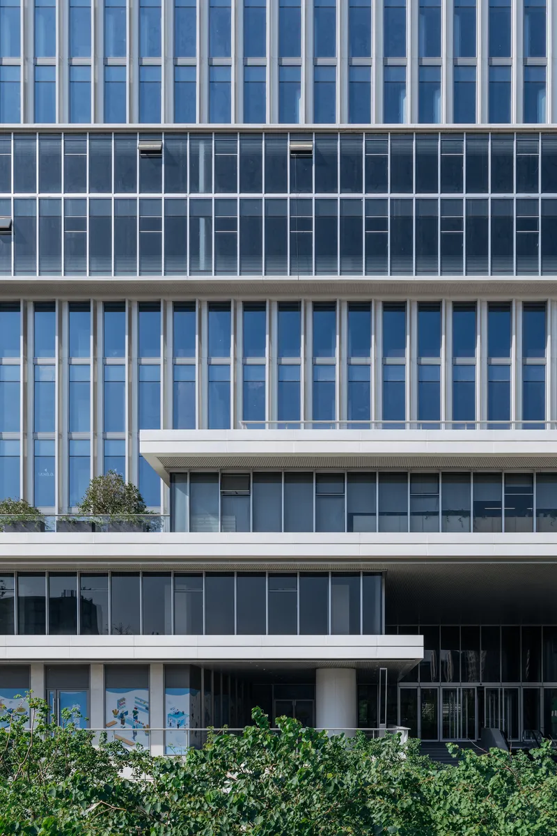 Layered horizontal glass and concrete facade with alternating vertical and horizontal fenestration patterns