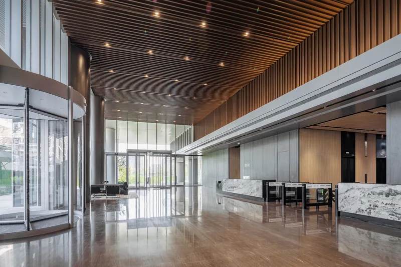 Lobby with timber slat ceiling, polished stone floors, and white marble reception desks