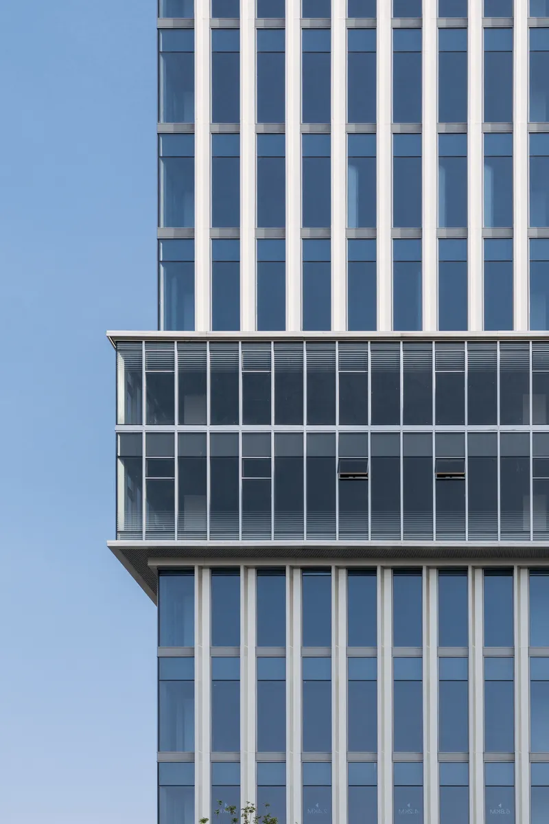 Corner detail of the cantilevered glass volume intersecting with the vertical glazed tower above