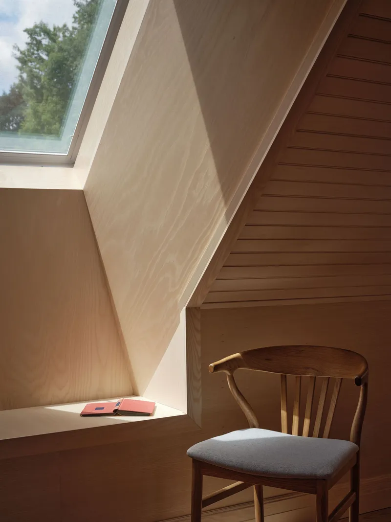 Built-in window nook with timber paneling and skylight casting daylight onto a reading chair
