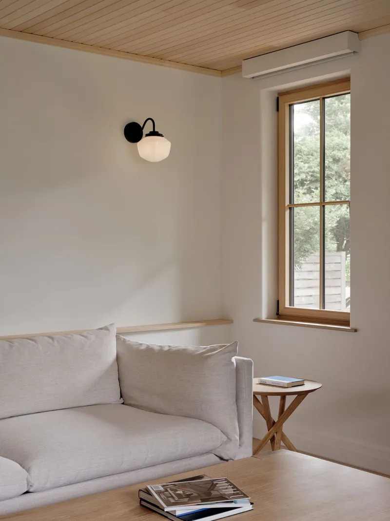 Sitting area with timber-framed window and wall-mounted sconce above a linen sofa