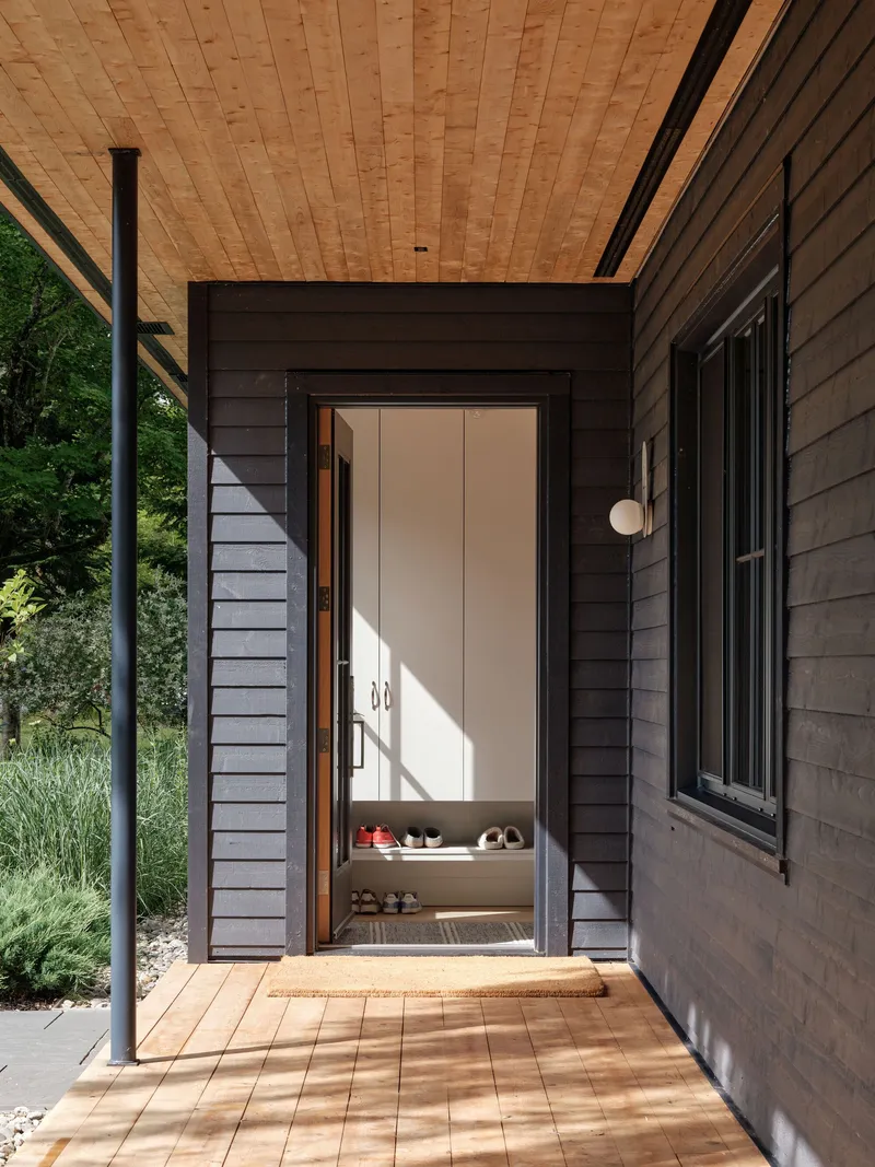 Entry threshold with timber decking leading to open door with shoes visible in afternoon sunlight
