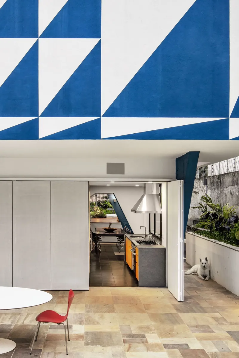 Covered terrace with patterned ceiling overhang looking into kitchen with sliding doors and planted bed
