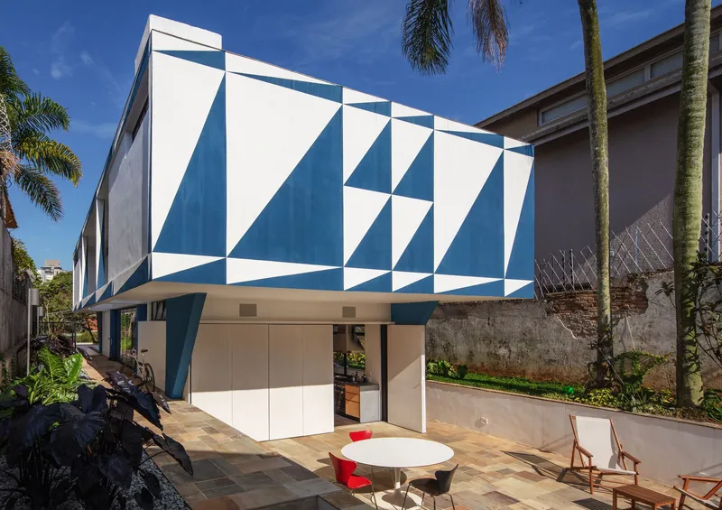 Street view of blue and white geometric tiled facade with open ground floor terrace under clear sky