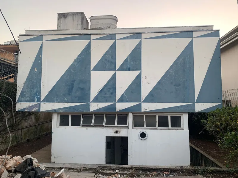 Rear elevation showing blue and white diagonal tile pattern above lower level windows at dusk