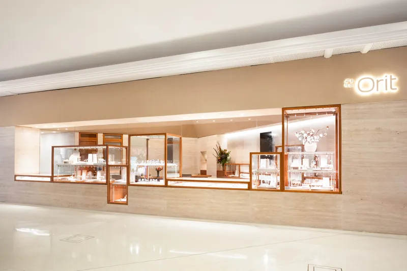 Travertine wall with staggered timber-framed glass display cases and concealed linear lighting above