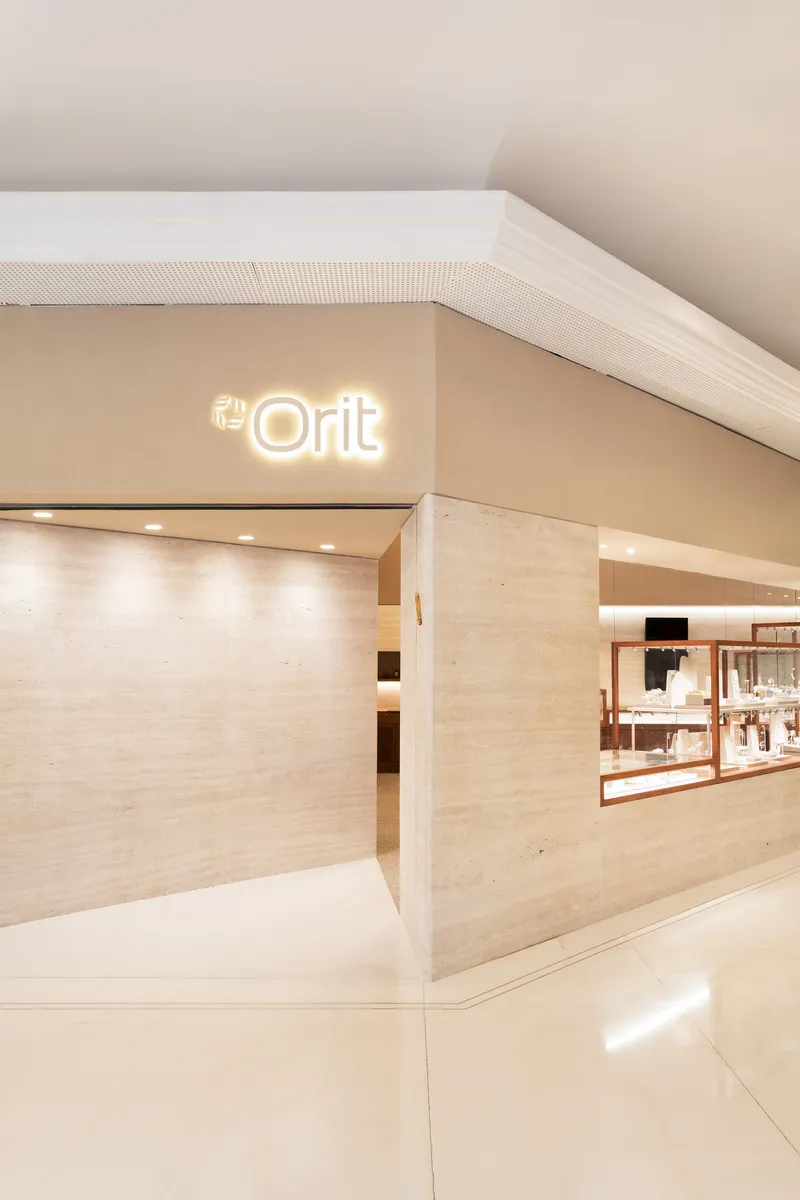 Angled view of the travertine-clad entrance volume with ribbed ceiling detail and glossy floor