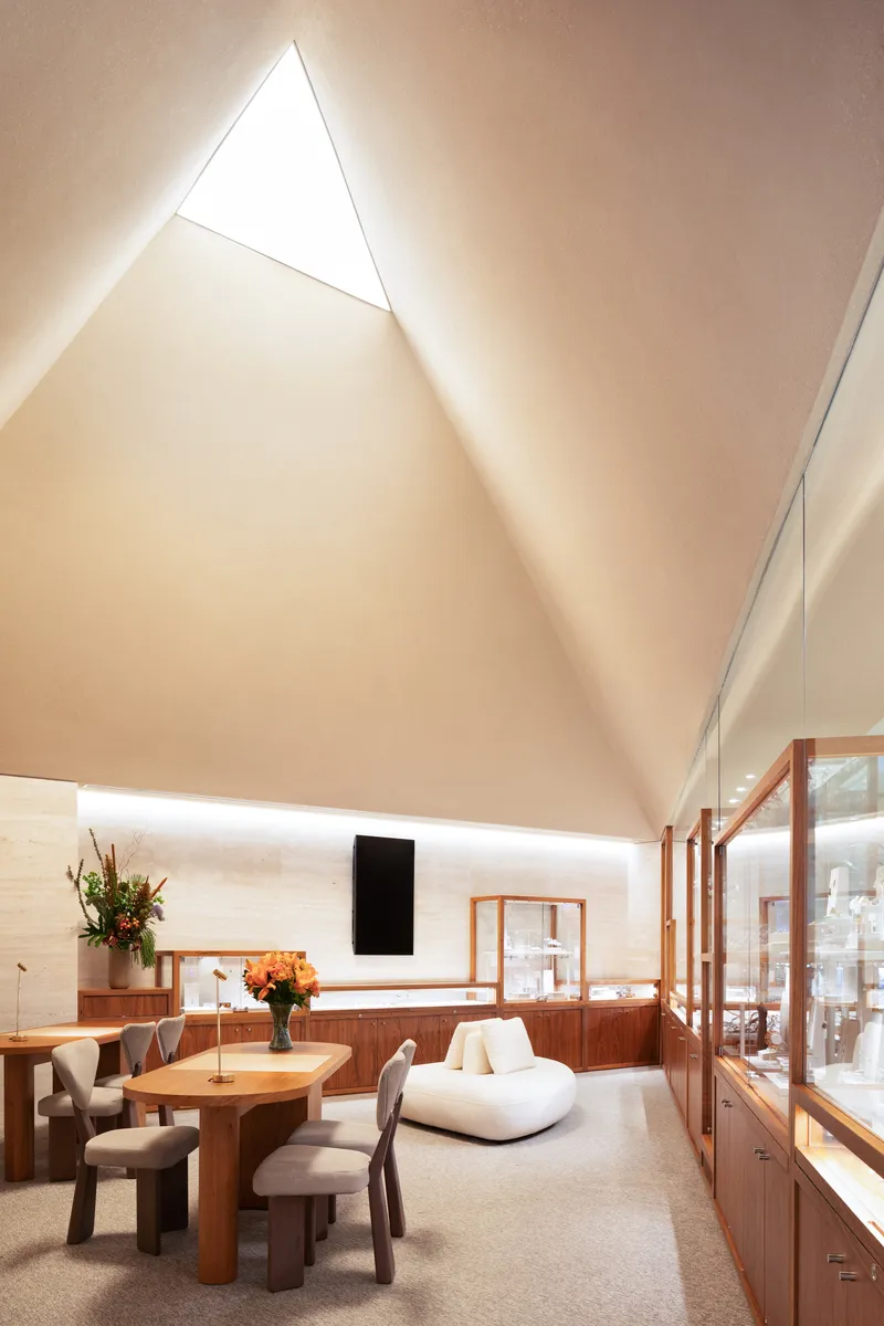 Triangular skylight with backlit cove illuminating the pitched ceiling above the seating area
