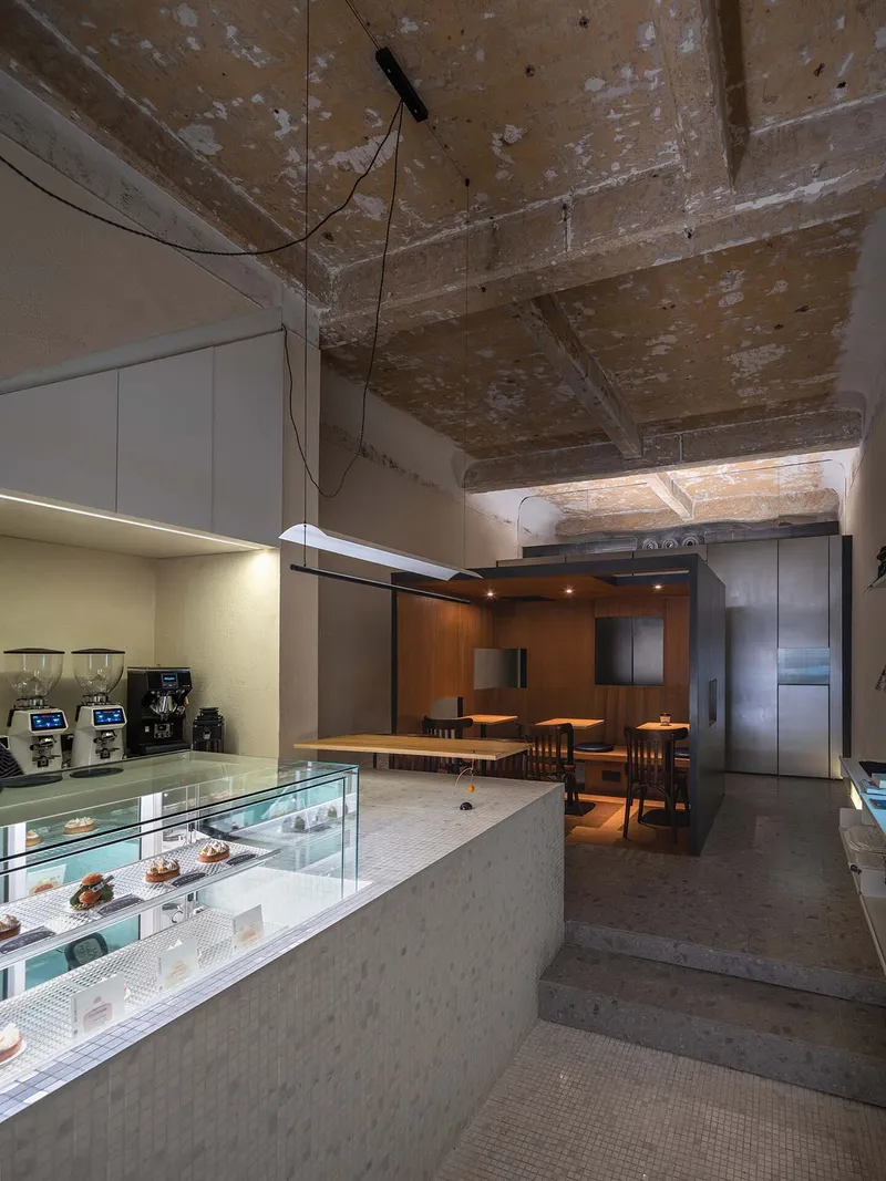 Interior view of display counter and dining area beneath exposed weathered concrete ceiling
