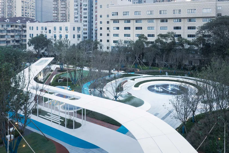 Elevated view of the white curving canopy threading through landscaped zones with newly planted trees