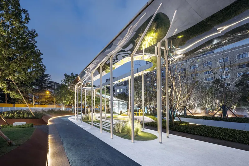 White steel column grid supporting the mirrored underside of the canopy at twilight