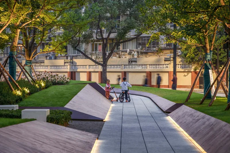 Folded timber deck pathway with integrated lighting where people walk beneath overhanging trees