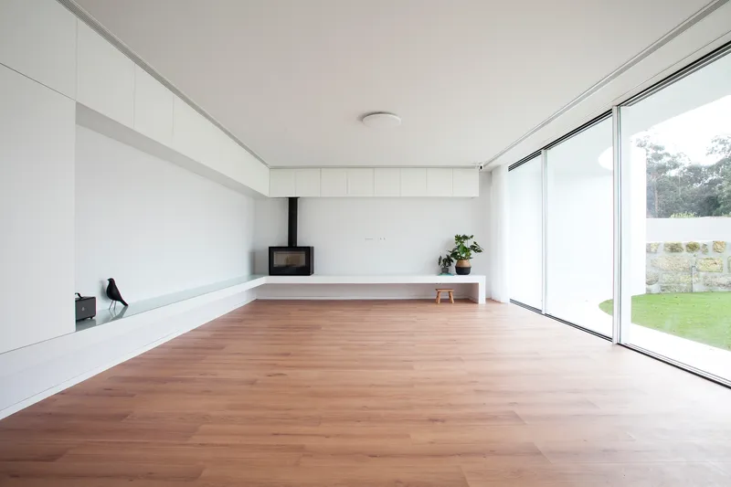 Open living space with wood flooring, freestanding stove, and floor-to-ceiling glazing to the garden