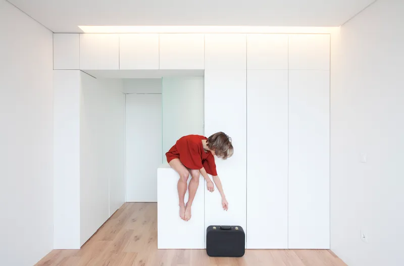 Interior room with seamless white storage wall and child jumping on wood floor