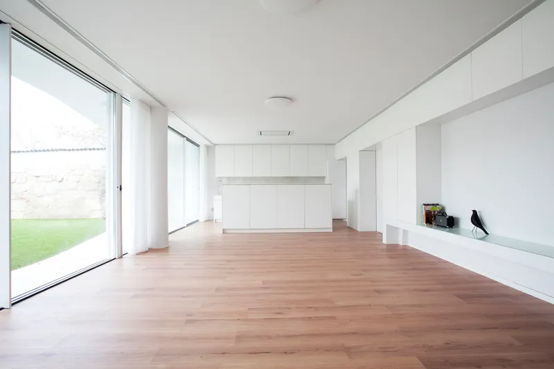 Open living area with timber flooring, white built-in storage, and glazed doors to lawn